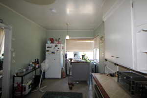 743-Kitchen with tile countertops, freestanding refrigerator, crown molding, white cabinetry, and light tile patterned flooring