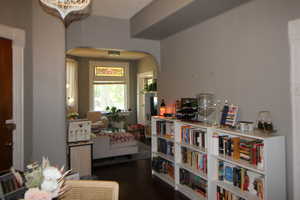 745-Sitting room with arched walkways, wood finished floors, and a chandelier