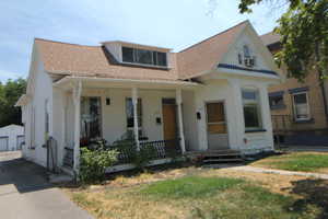 View of front of home featuring covered porch, roof with shingles, and a garage