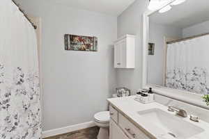 Full bath with vanity, curtained shower, and wood finished floors