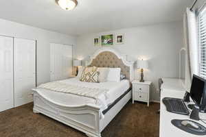 Bedroom featuring multiple closets and dark colored carpet