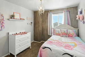 Bedroom featuring dark carpet and a chandelier