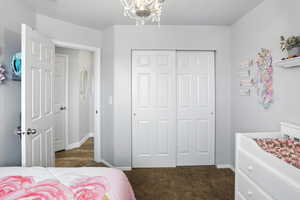 Bedroom featuring a closet, dark carpet, and a chandelier