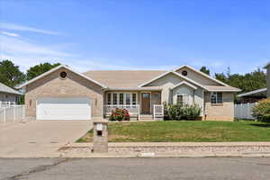 Single story home with a porch, concrete driveway, an attached garage, brick siding, and roof with shingles