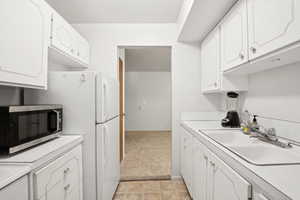 Kitchen with stainless steel microwave, light countertops, and white cabinetry
