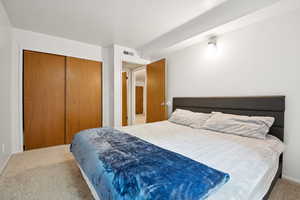 Bedroom with carpet, a closet, and a textured ceiling