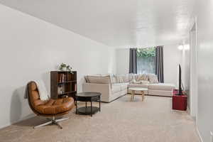 Living area featuring carpet flooring and a textured ceiling