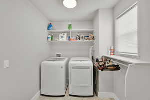 Laundry room featuring washer and clothes dryer and baseboards