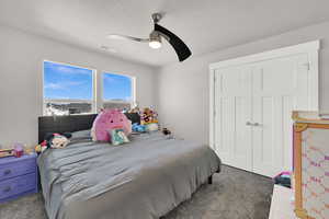 Carpeted bedroom with a ceiling fan, a closet, and a textured ceiling