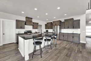 Kitchen with decorative backsplash, appliances with stainless steel finishes, wood finished floors, and recessed lighting