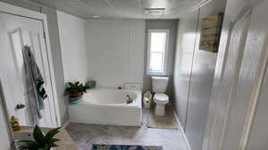 Full bathroom featuring a garden tub, crown molding, and a textured ceiling