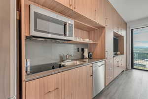 Kitchen with stainless steel appliances, modern cabinets, light wood-style flooring, and open shelves