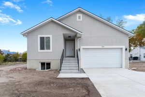 View of front of house with driveway, an attached garage, and stucco siding
