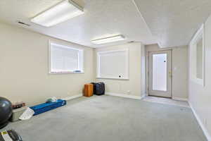 Empty room with a textured ceiling, carpet floors, and healthy amount of natural light