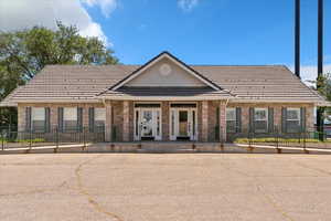 View of front of house featuring brick siding, covered porch, and uncovered parking