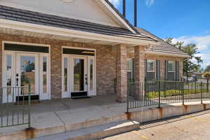 Doorway to property with a tile roof, brick siding, and a porch