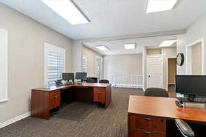 Office area featuring dark carpet and a textured ceiling