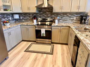 Kitchen with stainless steel electric range, wall chimney exhaust hood, backsplash, and dishwasher