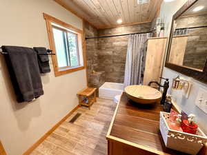 Bathroom with wooden ceiling, shower / bath combo with shower curtain, wood finished floors, and vanity