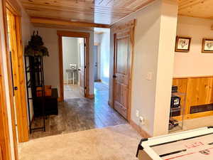 Hallway featuring wood ceiling, carpet flooring, and wood finished floors