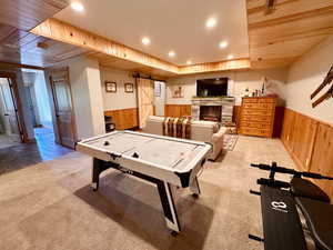 Rec room featuring a wainscoted wall, wooden walls, recessed lighting, carpet flooring, and a barn door