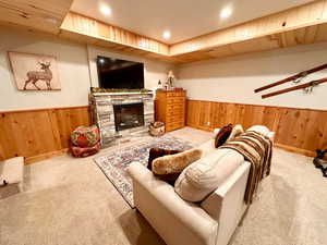 Living area with wood walls, wainscoting, a stone fireplace, recessed lighting, and carpet