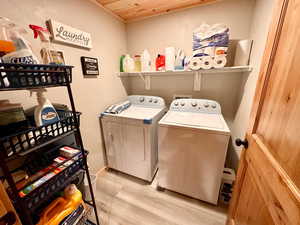 Washroom with separate washer and dryer, light wood finished floors, and wood ceiling