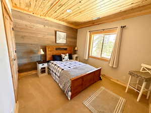 Carpeted bedroom with wood walls and wood ceiling