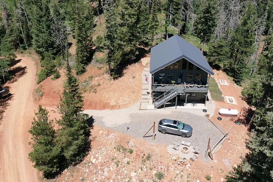 Aerial view of property and surrounding area with a forest