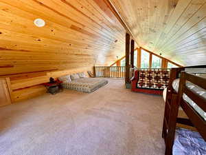Bedroom with wooden ceiling, carpet, lofted ceiling, and wood walls
