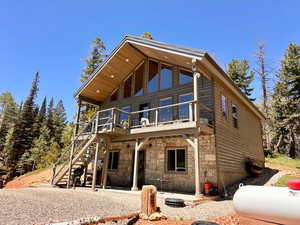 Rear view of house with stone siding, a patio area, and stairs