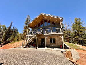 View of front of home with stone siding, a patio area, stairway, and a wooden deck