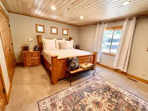Bedroom featuring wooden ceiling, recessed lighting, light carpet, and ornamental molding