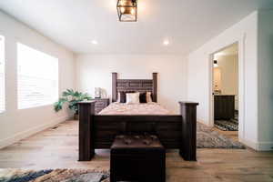 Bedroom with light wood-style flooring, recessed lighting, and connected bathroom