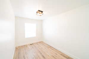 Spare room featuring light wood-type flooring and baseboards