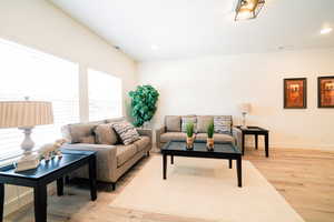 Living room with light wood-type flooring and recessed lighting