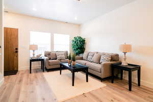 Living room with light wood-type flooring and recessed lighting