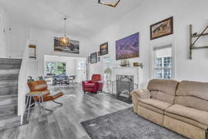 Living room with wood finished floors, ornamental molding, and a fireplace with flush hearth