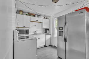 Kitchen featuring appliances with stainless steel finishes, white cabinets, concrete floors, and light countertops