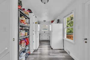 Kitchen with freestanding refrigerator, wood finished floors, and white cabinets