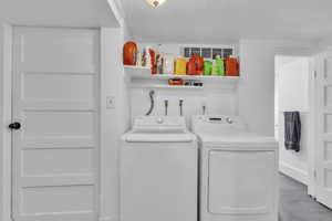 Washroom featuring independent washer and dryer and a textured ceiling