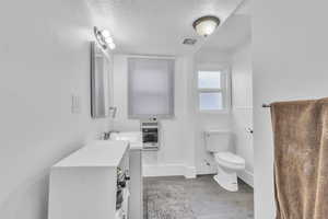 Bathroom with heating unit, wood finished floors, a textured ceiling, and vanity