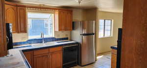 Kitchen with tile countertops, black appliances, brown cabinets, and light tile patterned floors