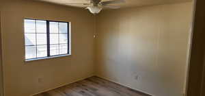 Empty room featuring a ceiling fan, wood finished floors, and a textured ceiling