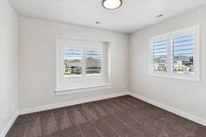 Unfurnished room with baseboards and dark colored carpet