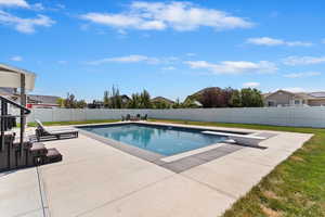 View of swimming pool featuring a patio area, a diving board, and a fenced backyard