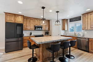 Kitchen with appliances with stainless steel finishes, recessed lighting, a center island, a kitchen bar, and light wood-style flooring