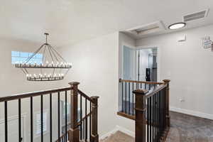 Staircase featuring carpet floors, a textured ceiling, and a chandelier