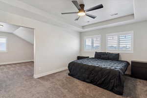Bedroom with carpet, a textured ceiling, a tray ceiling, and a ceiling fan