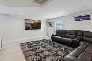 Living room with a textured ceiling, light wood finished floors, and recessed lighting